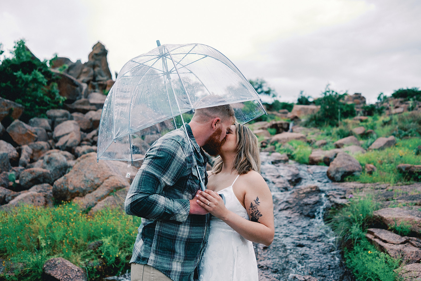 Couple under a umbrealla in the rain during an engagement session at Enchanted Rock State Park TX